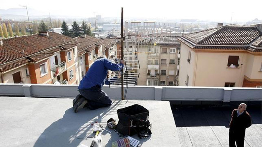 Un operario trabaja con antenas de televisión en un tejado. Archivo.
