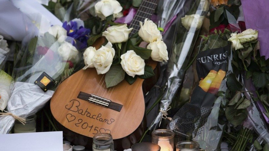Una guitarra rodeada de flores y velas encendidas que fueron depositadas frente a la sala de fiestas Bataclan en memoria de las víctimas de los atentados del viernes en París. EFE.