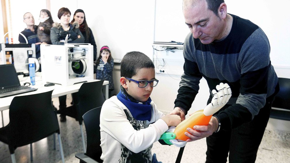 GRA213. ERRENTERÍA (GUIPÚZCOA), 08/02/2016.- El profesor del CIFP Don Bosco de Errenteria, Carlos Lizarbe (d), hace entrega a Unai Blanco (c), un niño de 7 años de A Coruña, de una prótesis de brazo impresa en 3D y construida para él entre alumnos y profesores de este centro educativo. EFE/Juan Herrero.