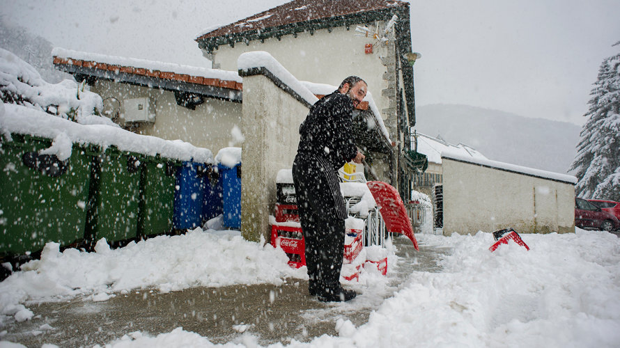 Un hombre retira la nieve acumulada a la entrada de su restaurante en Roncesvalles, (Navarra), localidad que hoy ha amanecido nevada debido a la progresiva bajada de la cota de nieve, que ha hecho que durante la noche se movilicen máquinas quitanieves de forma preventiva. EFE/VILLAR LÓPEZ