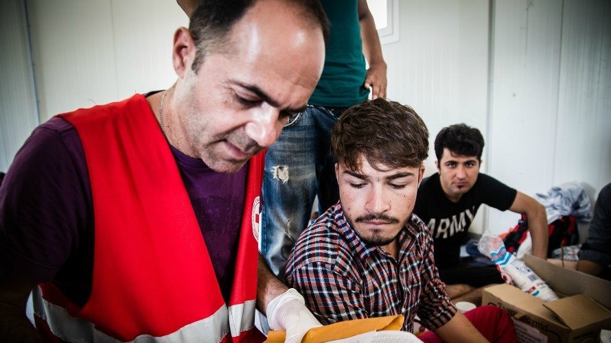 Un voluntario de Cruz Roja junto a varios refugiados.