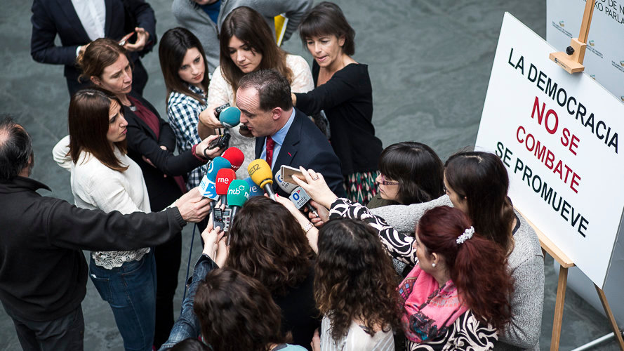 Javier Esparza, delante de la pancarta de denuncia que ha colocado UPN para reivindicar la retirada de la exposición del Parlamento foral. PABLO LASAOSA