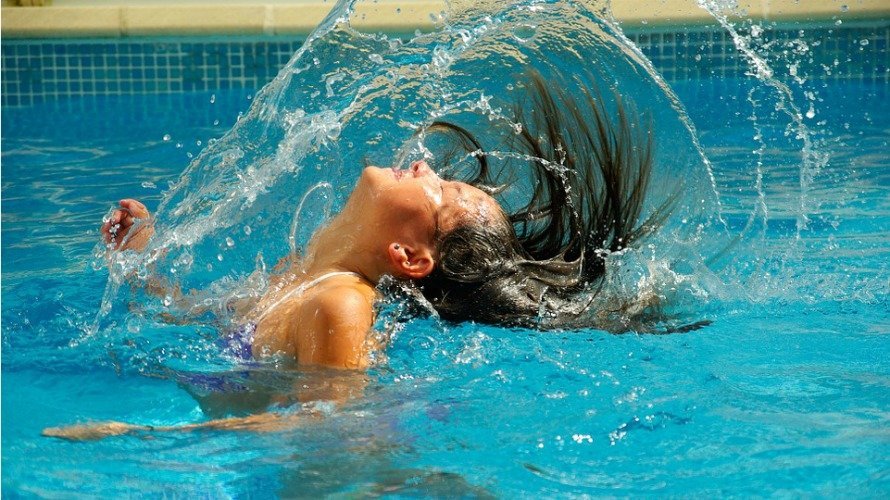 Una niña disfruta de la estación de verano en la piscina. 