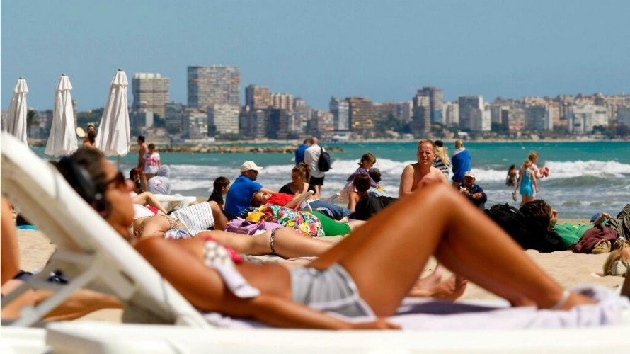 Una mujer se protege del sol con unas gafas mientras se broncea en la playa. EFE