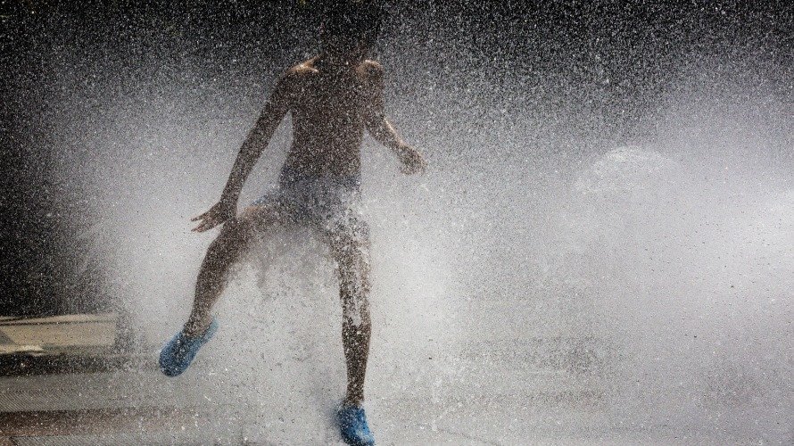 Un niño salta y juega en una fuente de Pamplona disfrutando del calor y de las altas temperaturas del verano. Tiempo. EFEVillar López
