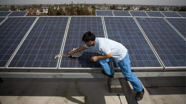 Un trabajador limpia una placa solar en la azotea de un edificio EFE