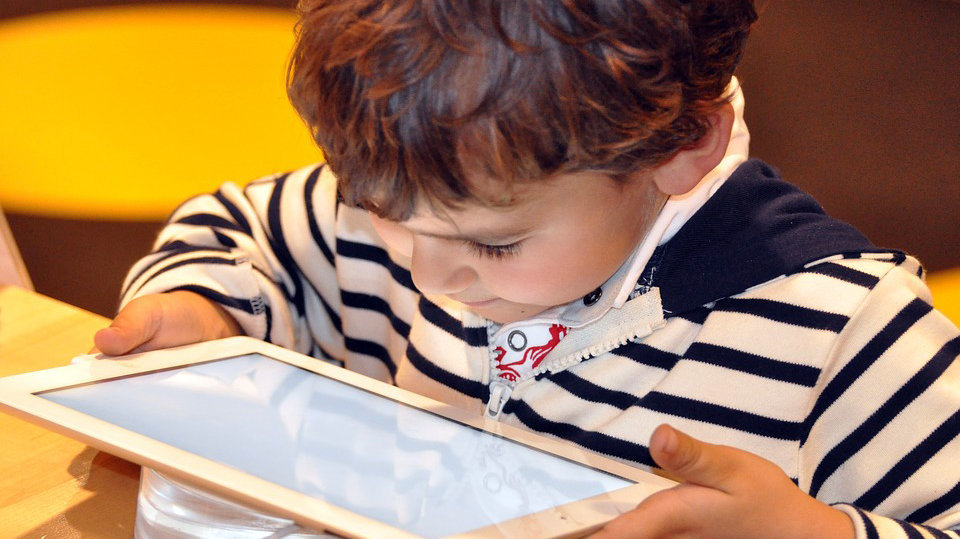 Un niño mira fijamente la pantalla de una tablet.