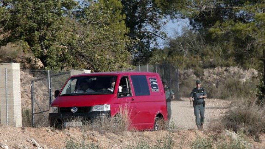 El furgón del reten fúnebre pasa junto a dos agentes de la Guardia Civil en el lugar donde se ha encontrado el cadáver de la joven de 15 años desaparecida en Chella. EFE
