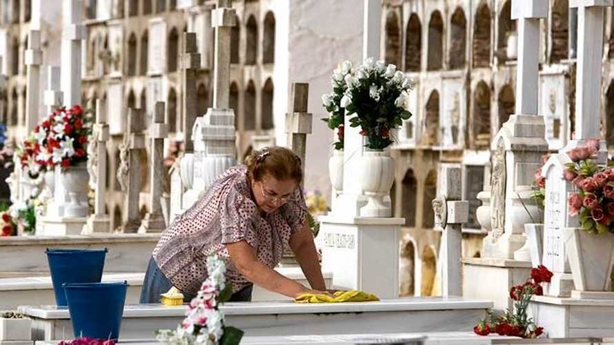 Mujer limpiando una tumba de suelo en el cementerio. EFE