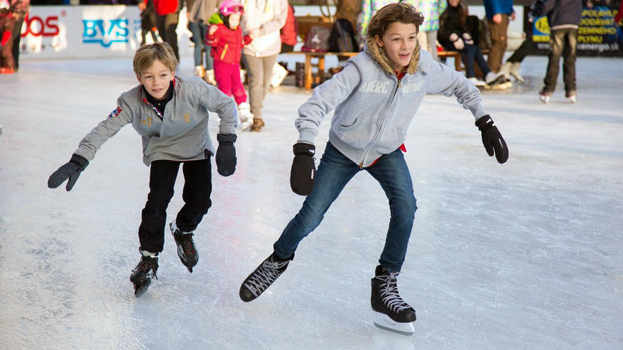 Dos chicos patinan en una pista de hielo.