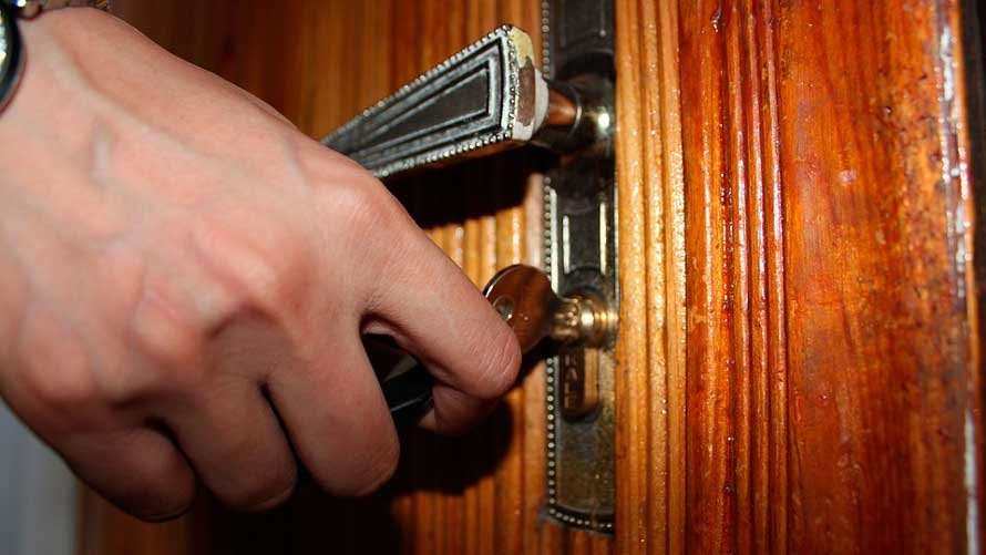 Mujer abriendo con una llave la cerradura de una casa.