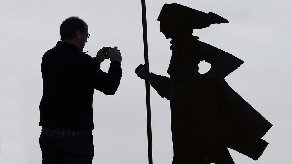 Una persona toma fotos de la niebla que cubre la comarca de Pamplona junto a una de la figuras del Camino de Santiago situadas en la sierra del Perdón. EFE/Jesús Diges