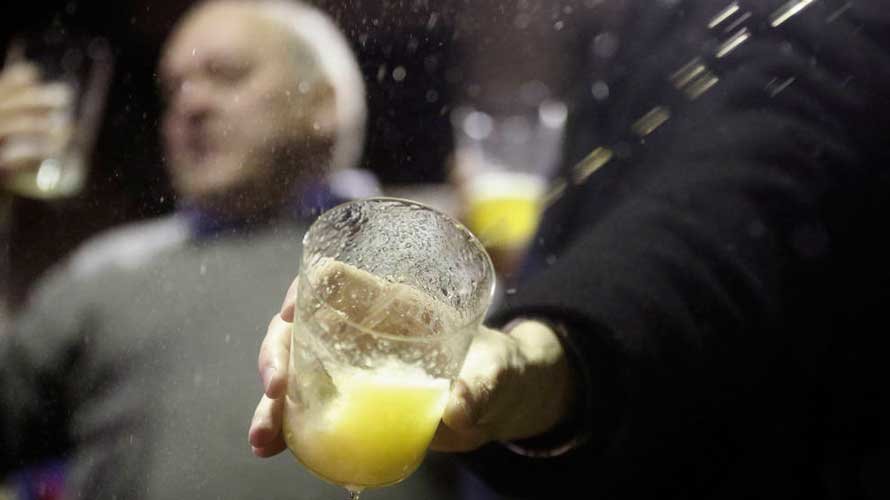Un hombre llena su vaso de sidra en la celebración del 'txotx' en una de las sidrerías tradicionales. EFE.