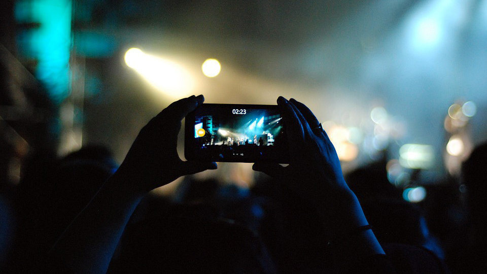 Un joven graba con su teléfono móvil un concierto de música en una discoteca ARCHIVO
