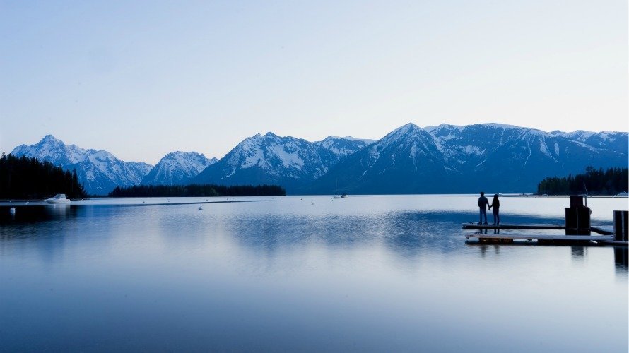 Una pareja contempla un gran lago y montañas nevadas.