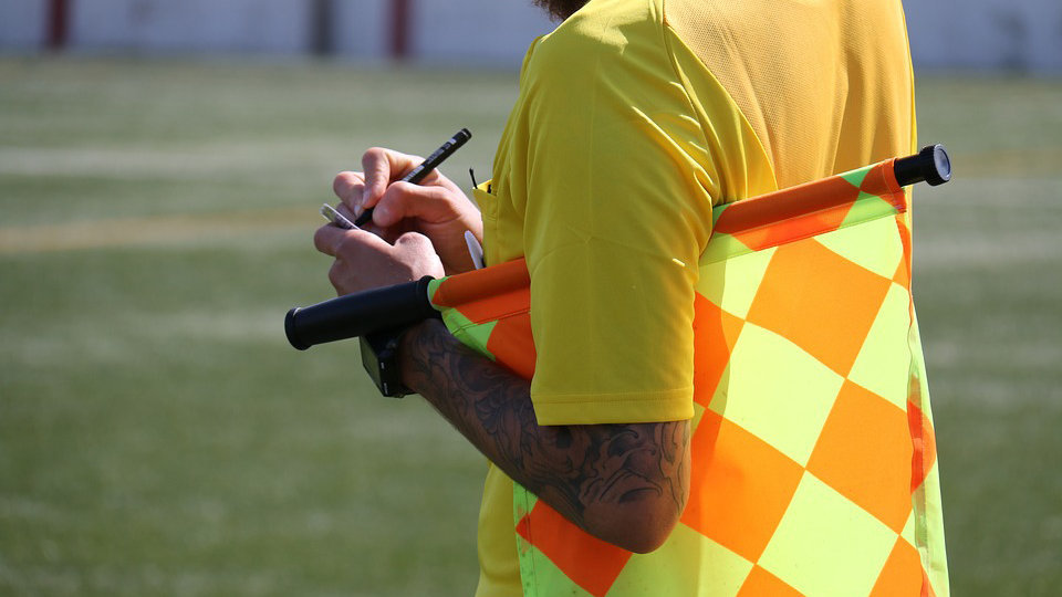 Imagen de un árbitro con el banderín y anotando una falta cometida durante un partido de fútbol ARCHIVO
