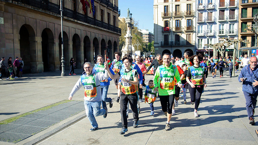 Laura Berro y Alberto Labarga (Aranzadi-Podemos) corren con el testigo de la ikurriña de la Korrika en Pamplona. MIGUEL OSÉS