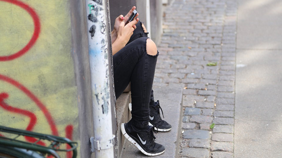 Una joven mira el móvil en la calle