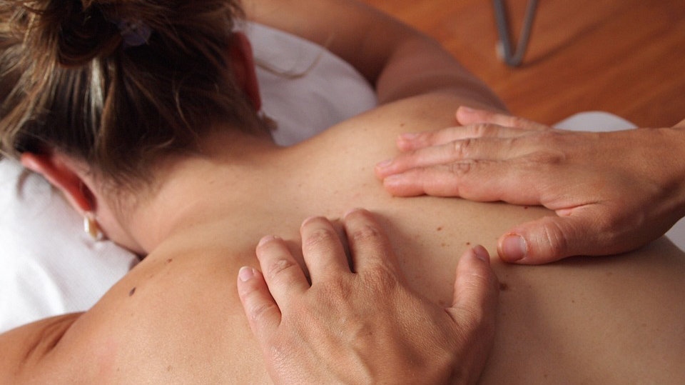 Un fisioterapeuta da un masaje en la espalda a una paciente.