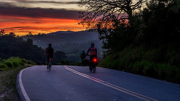 Imagen de varios ciclistas circulando por la carretera con las luces de señalización durante el atardecer ARCHIVO