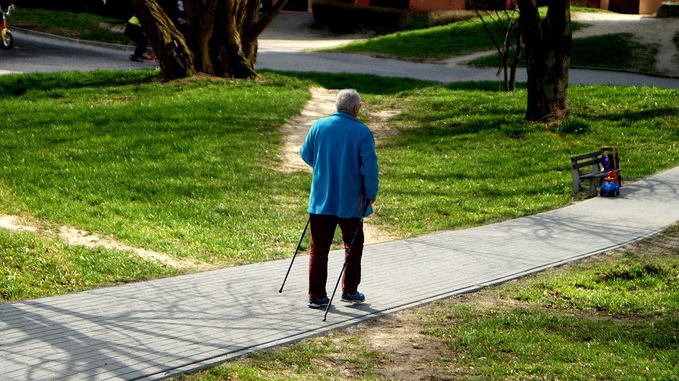 Un hombre mayor camina por un paseo ayudándose con dos bastones ARCHIVO