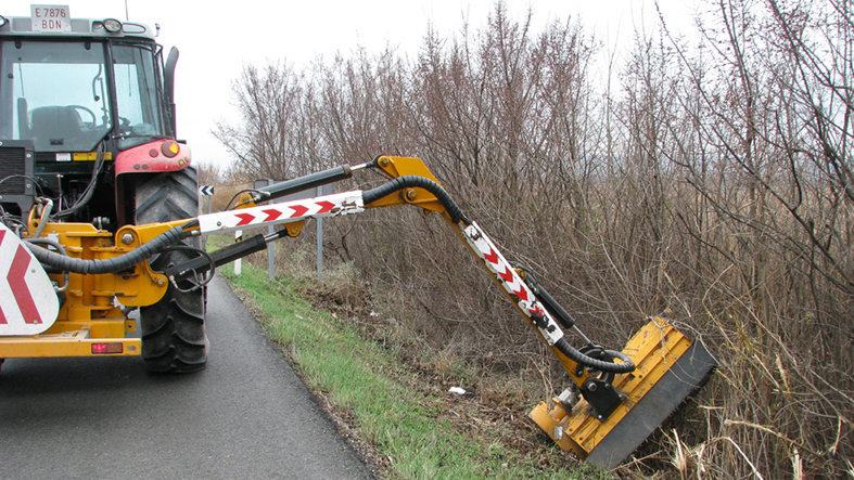 Imagen de un tractor pala recortando la vegetación de la cuneta de una carretera navarra GURELUR