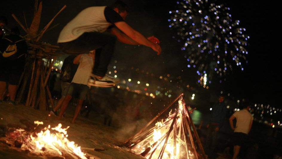 Un hombre salta una hoguera en la noche de San Juan en una de las celebraciones organizadas en Galicia EFE