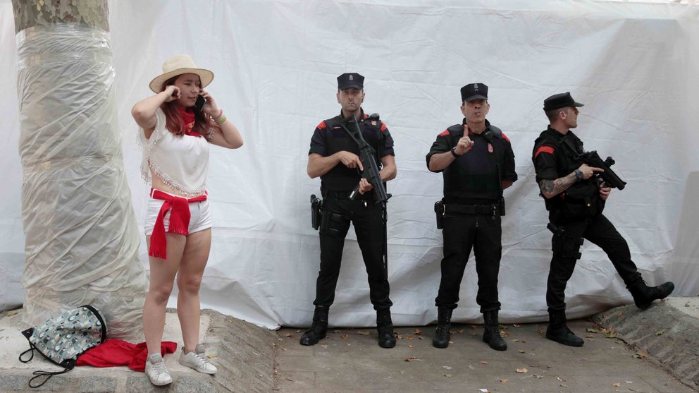 PAM03. Pamplona (Spain), 09/07/2017.- A reveller wearing the traditional red and white clothes that are standard Rae speaks on her cellphone next to a group of Spanish armed police outside the bullring as the crowd leaves during the Festival of San Fermin 2017 in Pamplona, Spain, 09 July 2017. Pamplona has increased security during the internationally famed festival that attracts large crowds of visitors. The festival, locally known as Sanfermines, is held annually from 06 to 14 July in commemoration of the city's patron saint. (España) EFE/EPA/JIM HOLLANDER