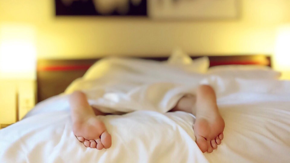 Una persona duerme tumbada bocabajo en una cama cubierta por un edredón ARCHIVO