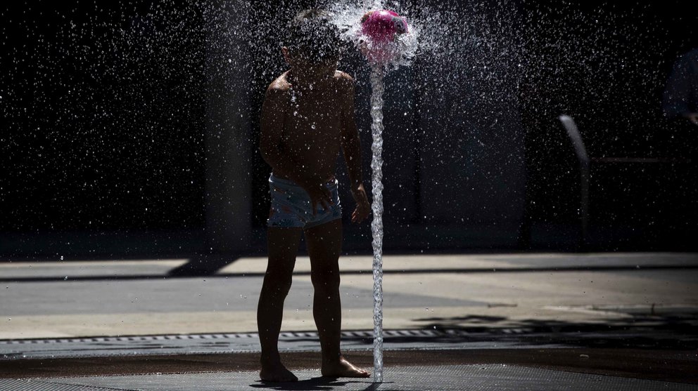Un niño se divierte con el agua de una fuente de Pamplona, en una jornada donde las temperaturas han alcanzado los 33 grados en la capital navarra y el cielo aparece completamente despejado. EFE/Villar López