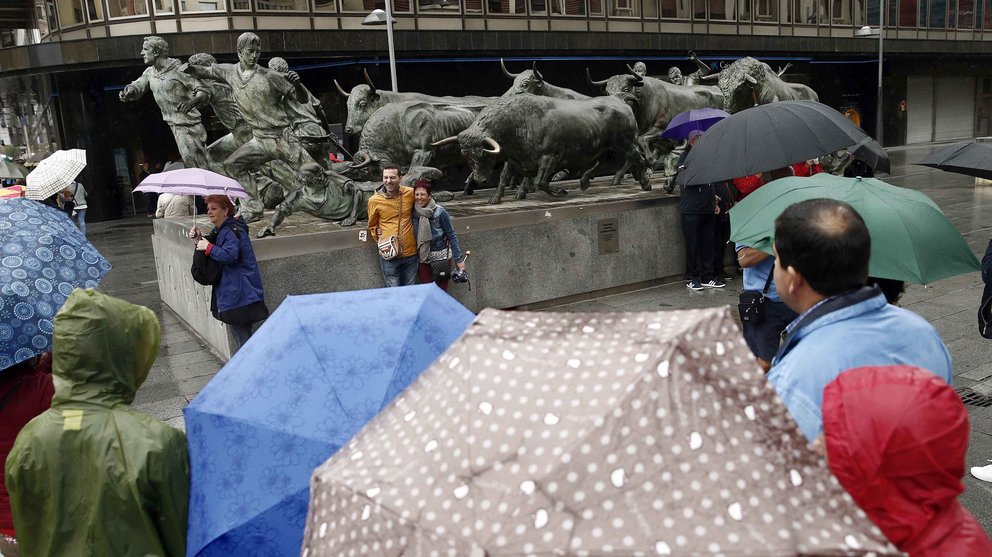 Un grupo de turistas se fotografían junto al Monumento al Encierro en Pamplona en una jornada donde las temperaturas, que no sobrepasan los 15 grados, y la lluvia hacen que el día sea mas típico del otoño que de agosto. EFE/Jesús Diges
