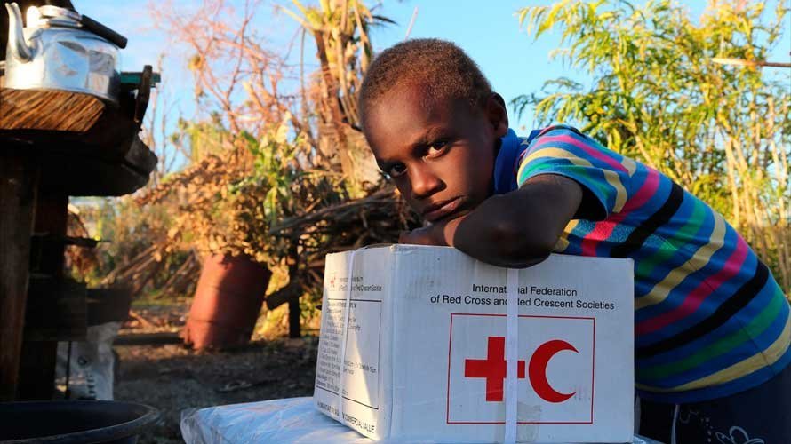 Imagen de un niño con la caja de ayuda humanitaria de Cruz Roja. CRUZ ROJA