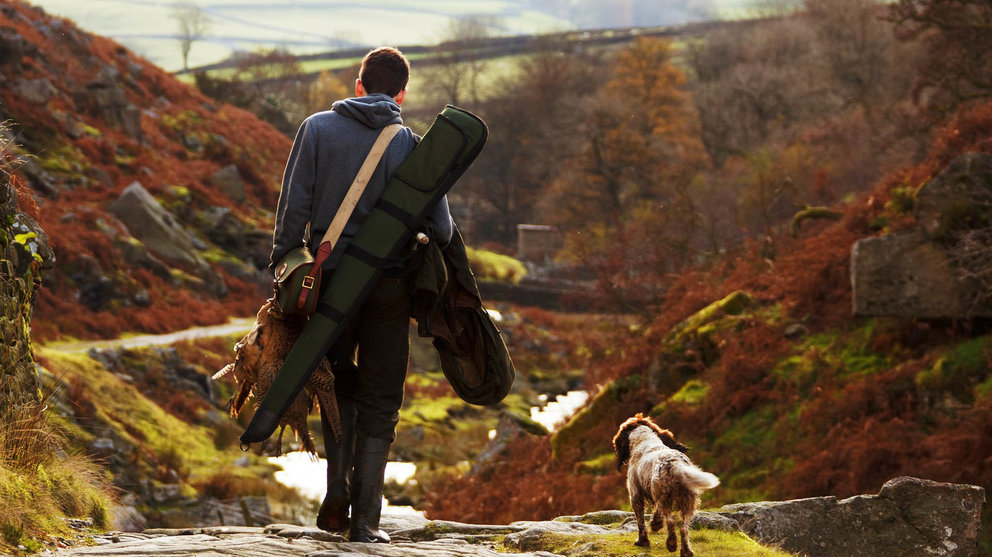 Una cazador camina junto a su perrro por una zona habilitada para la caza.