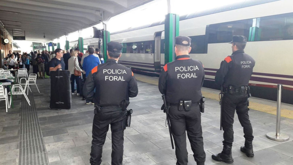 Agentes de la Policía Foral viviglan la estación de Renfe en Pamplona mientras varios viajeros suben al tren POLICÍA FORAL