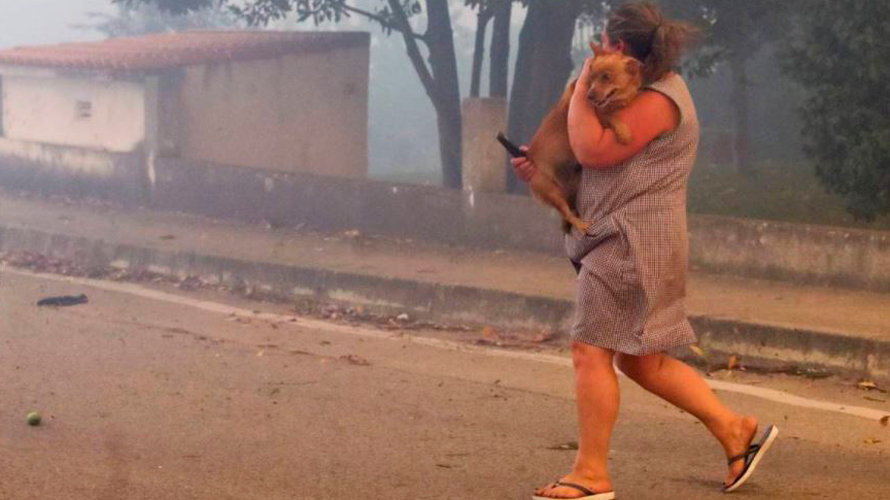 Una mujer corre con su perro en un pueblo del norte de Portugal ante la próximidad de las llamas EFE