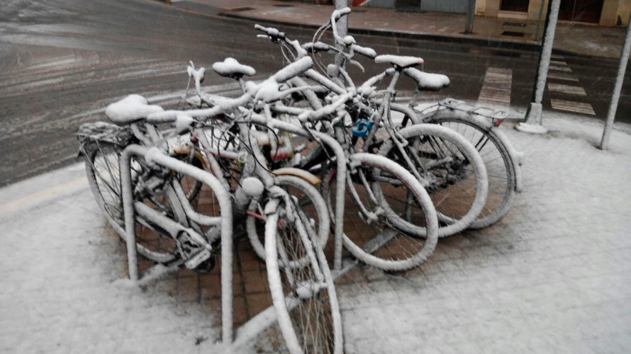 Varias bicicletas aparcadas en Pamplona y cubiertas de nieve.