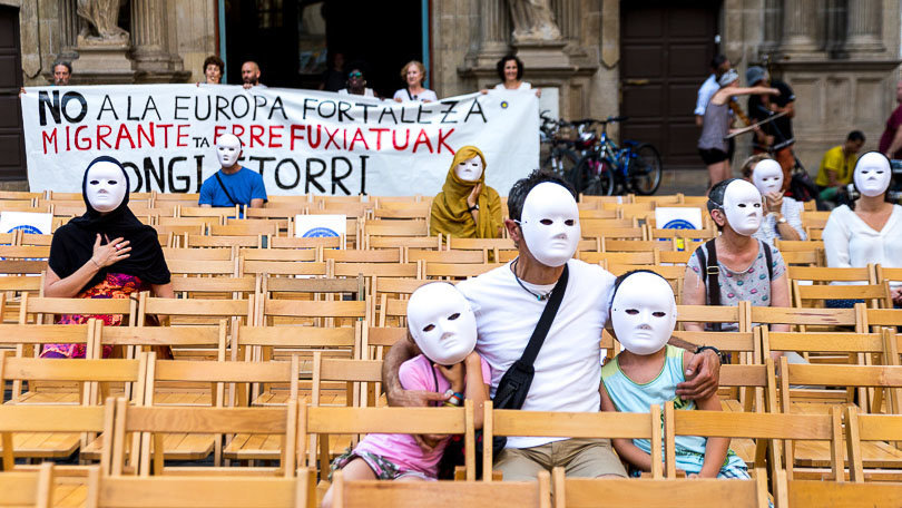 Varias personas reclaman un mejor trato para los refugiados durante un acto de la Plataforma Pamplona Ciudad de Acogida. ALZUGARAY