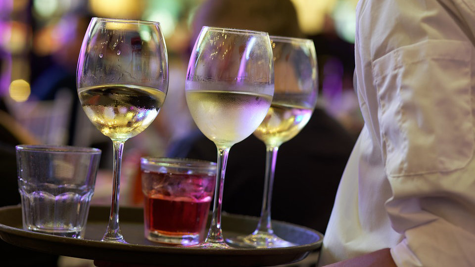 Imagen de una camarera con una bandeja sirviendo varias copas en un bar ARCHIVO