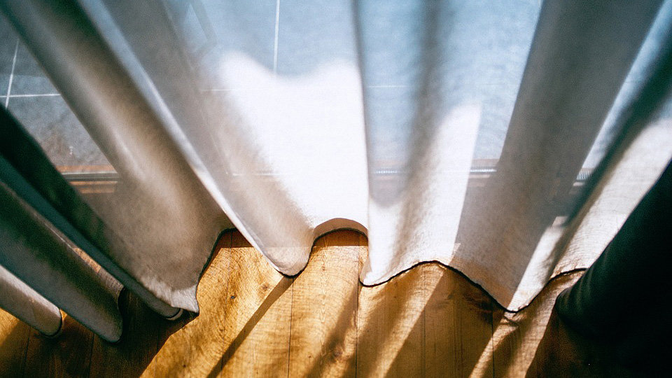 Imagen de una cortina cubriendo una ventana donde refleja la luz del sol en una vivienda ARCHIVO
