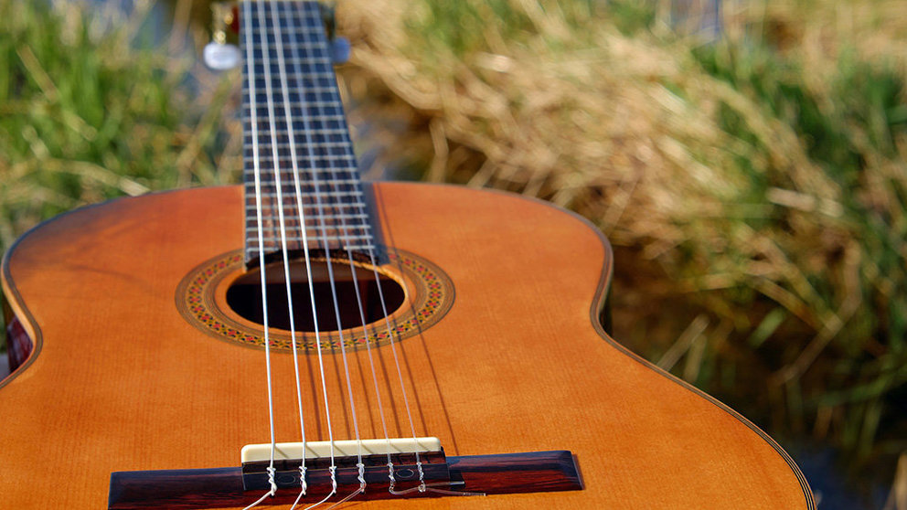 Una guitarra acústica sobre un campo ARCHIVO
