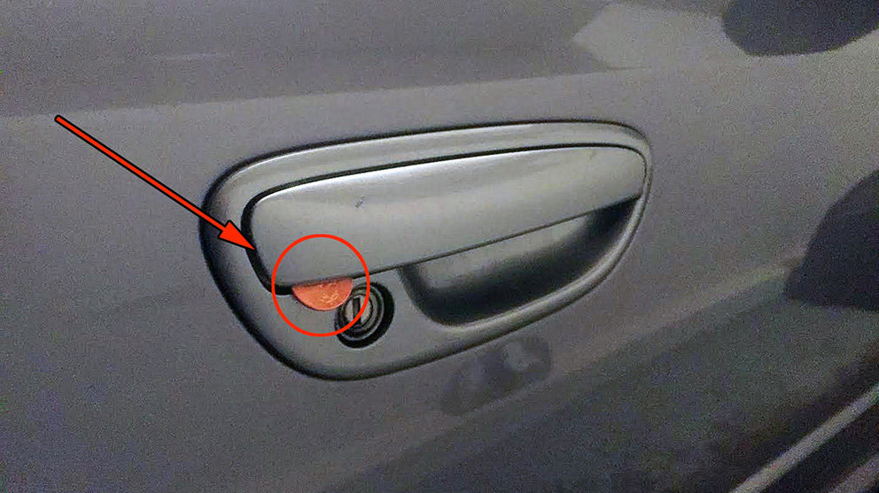 Imagen de una moneda insertada en la manilla de la puerta de un coche para evitar que se active el cierre de seguridad del vehículo YOUTUBE