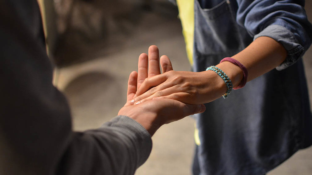 Dos personas unen sus manos en gesto de solidaridad.