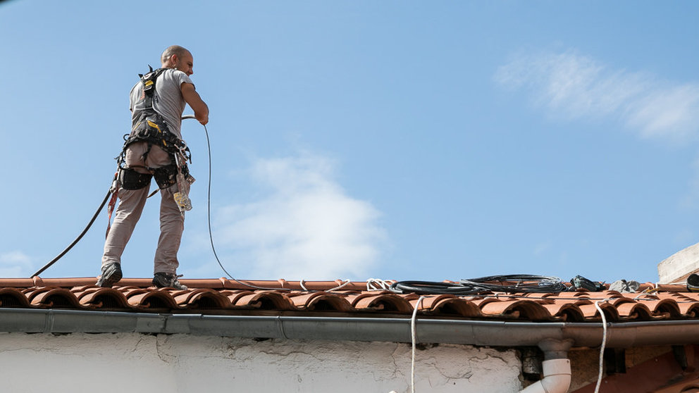 Un operario trabaja en la instalación del cable de fibra óptica en un tejado de Pamplona (03). IÑIGO ALZUGARAY