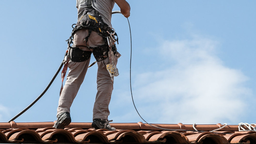 Un operario trabaja en la instalación del cable de fibra óptica en un tejado de Pamplona (04). IÑIGO ALZUGARAY