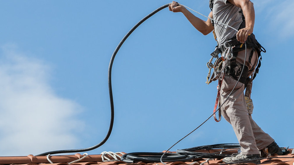 Un operario trabaja en la instalación del cable de fibra óptica en un tejado de Pamplona (08). IÑIGO ALZUGARAY