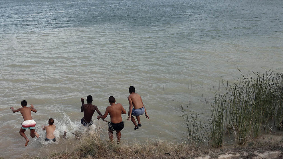 Un grupo de jóvenes disfrutan de un baño para combatir el calor en la balsa de La Morea, en la localidad navarra de Beriáin, antes de que una pequeña tormenta atravesara la zona. EFE/Jesús Diges