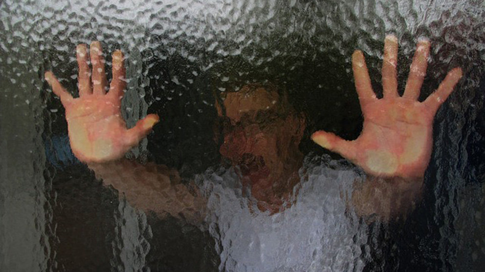 Un joven, detenido como agresor de un caso de violencia sexita, apoya sus manos contra el cristal de una puerta. ARCHIVO