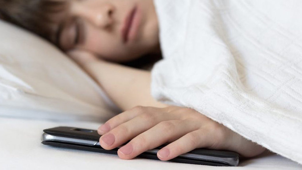 Un trabajador se queda dormido en su cama con el móvil de trabajo en la mano, uno de los factores que más afecta a la hora de sufrir estrés ARCHIVO