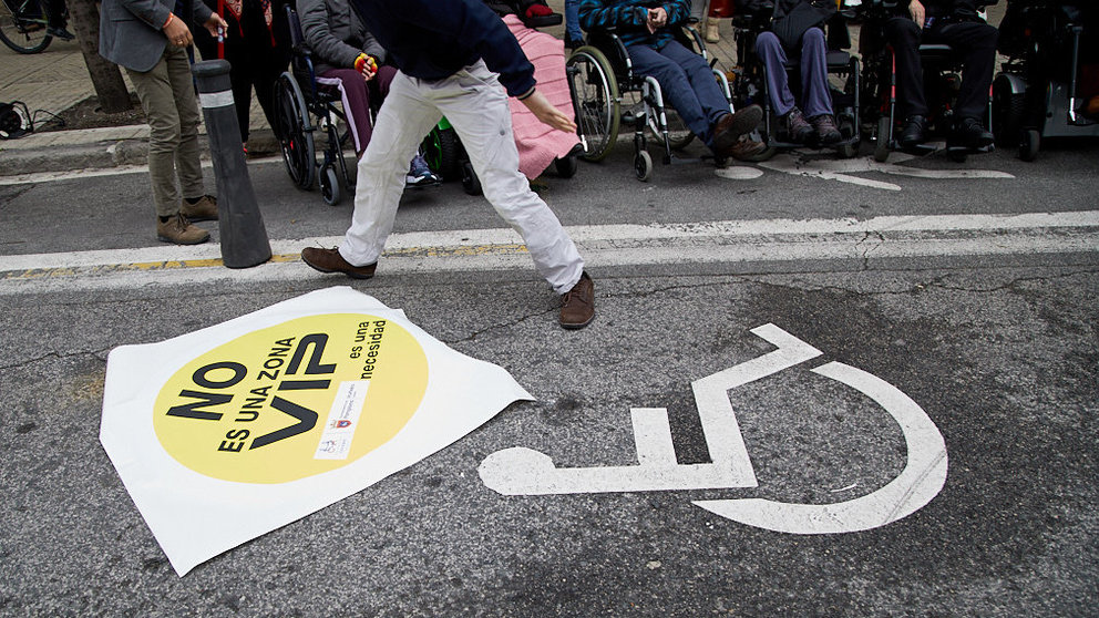 Cocemfe Navarra lleva a cabo la colocación de la primera pegatina dentro de la campaña para respetar la reserva de plazas de aparcamiento para personas con discapacidad. IÑIGO ALZUGARAY