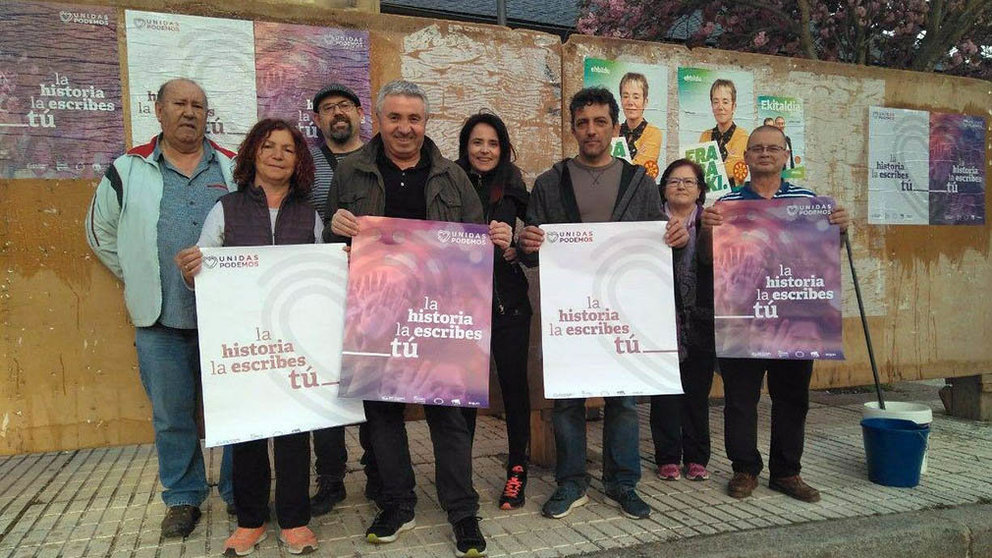Imagen de los candidatos de Podemos en Tafalla con los carteles de Bildu en segundo pleno.